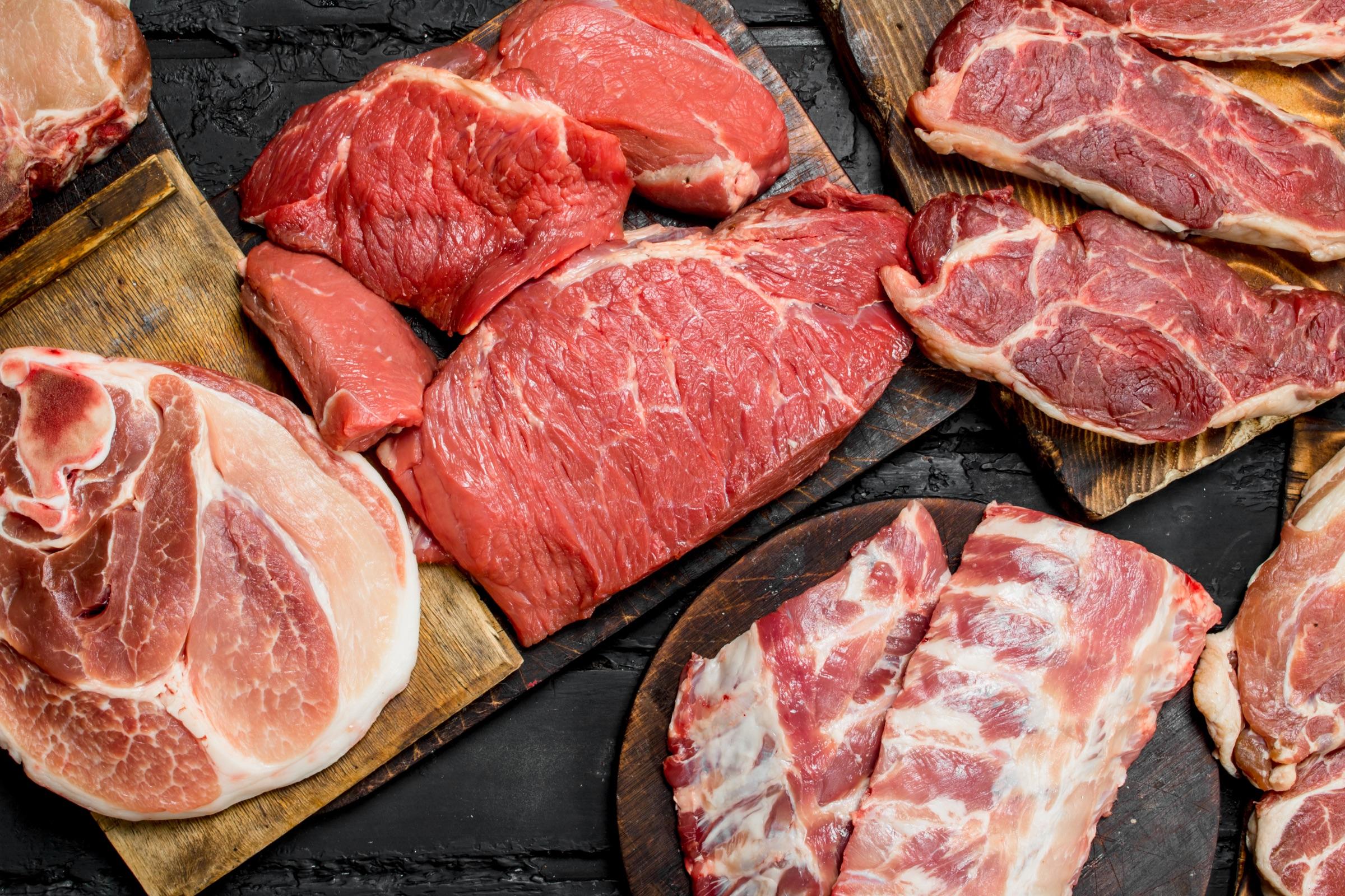 Assorted fresh meat cuts on wooden boards